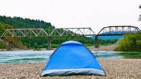 Riverside Retreat: Camping Tent nestled by the Gravelly River Bank in the Serene Wilderness