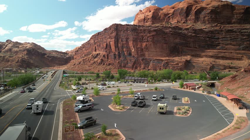 Aerial pull away from parking lots and bike path on highway 191 along Colorado River through Moab Utah in spring time