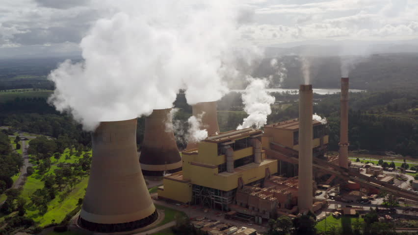 Fly into coal-fired power station. Yallourn thermal power plant, one of Australia’s largest electricity generators, burns fossil-fuels to generate steam, seen billowing in clouds from cooling towers. Royalty-Free Stock Footage #1103747895