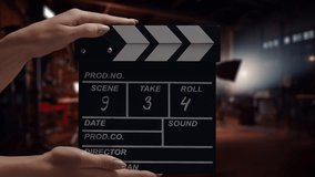 Human hands are using a clapperboard on set. Beginning of scene in film or TV television production. Concept of cinematography movie or video crew. Stage and filmmaking equipment background