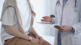 Doctor is using tablet computer while patient is sitting near. Unknown senior physician is at work. Medicine and health care concept