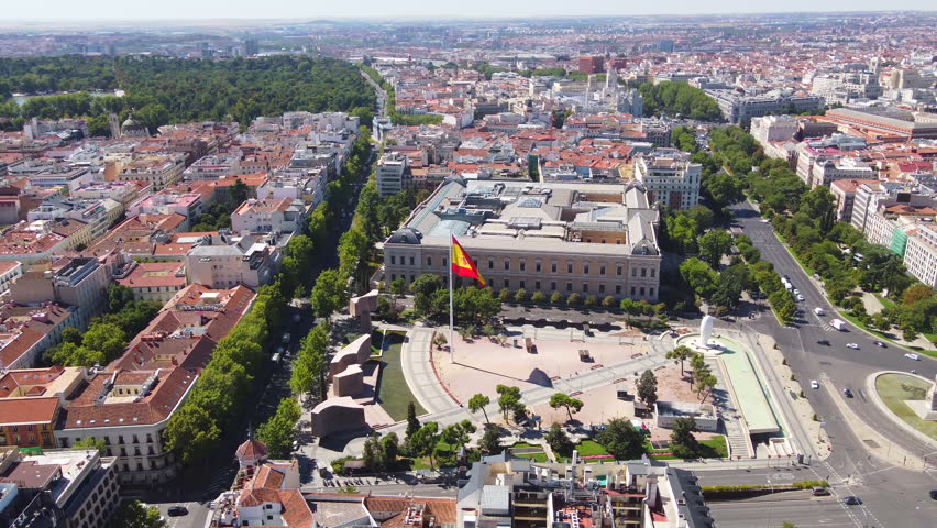 View from the drone to the center of the city of Madrid, bustling traffic monument to Christopher Columbus rooftops and cultural buildings under construction skyscraper and flag of Spain city streets