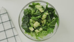 The woman makes salad dressing using lemon, olive oil, salt, and black pepper. Lettuce, fresh avocado, and celery green salad recipe