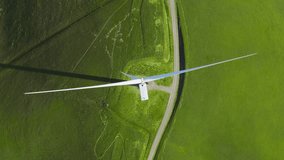 Aerial top down view of wind turbine providing sustainable energy by spinning blades. Eco friendly power electricity generation by natural renewable wind resources on green field meadow background 4K - Powered by Shutterstock - Get 15% off with code: PIKWIZARD15