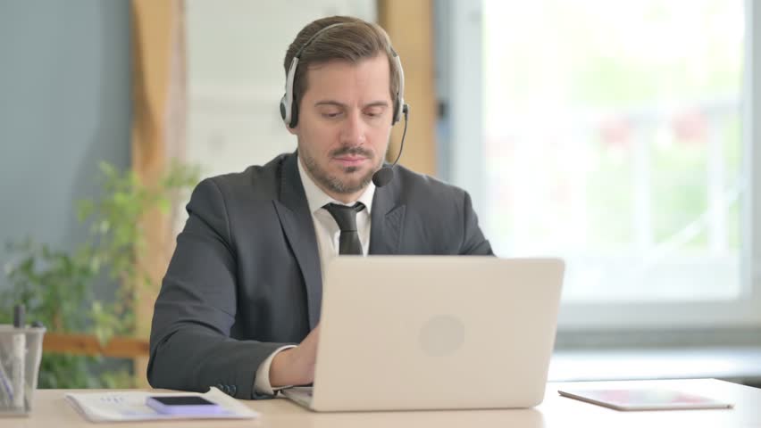 Young Man with Headset Talking with Customers Online in Call Center Royalty-Free Stock Footage #1103754419