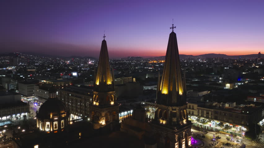 Beautiful purple pink sunset sky above Guadalajara city in Mexico. Drone of historic architecture Cathedral with night illumination. Aerial Guadalajara Cathedral and Central Plaza Jalisco. Latin city