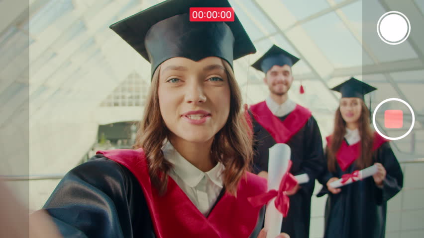 In Front of the Camera, Girl Graduate Made a Selfie Video Discussing Something After Graduation she Holds the Camera with One Hand in the College Hallway Royalty-Free Stock Footage #1103759157