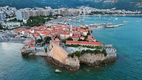 Port with ships and boats for excursions on the Adriatic Sea near the island of St. Stevan in the evening city of Budva against a romantic cloudy sky