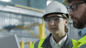 Male and Female mechanical engineers talking at industrial factory. Bearded male holds laptop and explains task to colleague at construction site. Background of work process. - Powered by Shutterstock - Get 15% off with code: PIKWIZARD15
