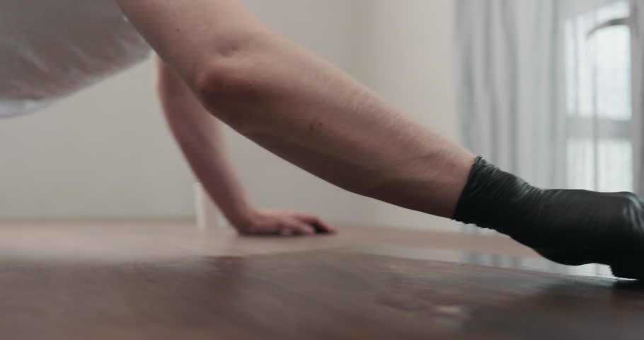 Slow motion of man hand applying oil finish to toned walnut table with cloth