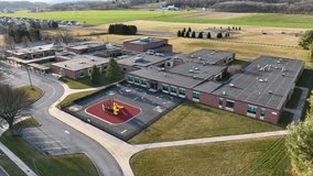 Aerial view of a school campus. Brick exterior of building and fenced in playground for recess. - Powered by Shutterstock - Get 15% off with code: PIKWIZARD15