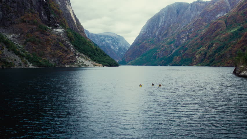 Group of friends in yellow kayaks paddle in epic majestic norwegian fjord. Aerial drone shot of kayak group in scenic location. Holiday travel in Norway Royalty-Free Stock Footage #1103773781