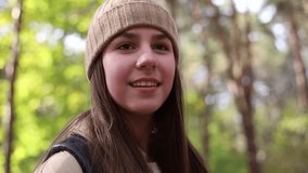 American teenage girl hiking with backpack in forest woodland. Video portrait of hiking teenager girl. Sport healthy concept.