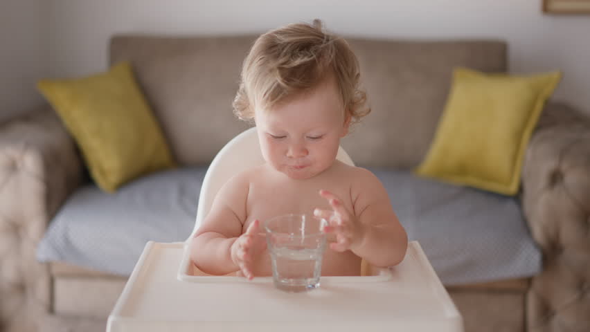 Cute child boy drinking a glass water at home. Slow motion of little boy drinking water. Closeup. Child drinking a cup water with of lemon - healthy body care. slow motion shot. Cute hispanic baby