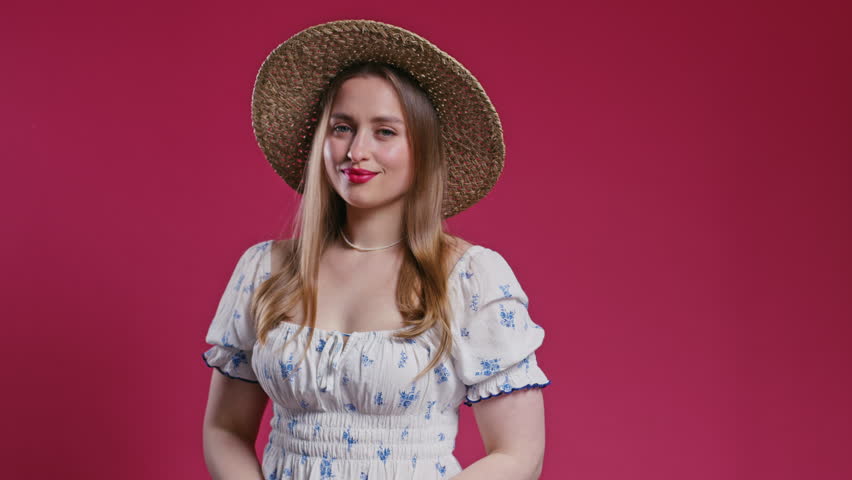 Beautiful woman portrait in stylish outfit with straw hat on red. Summer vibes.
