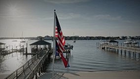 The North Carolina state flag flies alongside the stars and stripes in a coastal setting. - Powered by Shutterstock - Get 15% off with code: PIKWIZARD15