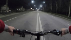 Person riding bicycle in center of automobile paved street road in night city. Man riding bike in town at evening. POV. Cycling urban outdoors. Leisure entertainment sports recreation activity extreme - Powered by Shutterstock - Get 15% off with code: PIKWIZARD15