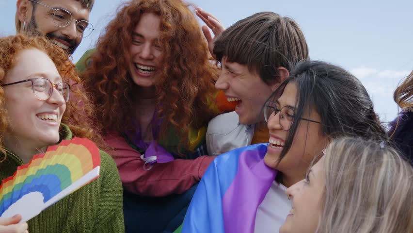 Cheerful smiling diverse group of young friends together celebrating gay pride day. Happy people from the LGBT community enjoying the outdoors. Lesbian, homosexual, transgender and non binary people. Royalty-Free Stock Footage #1103790283