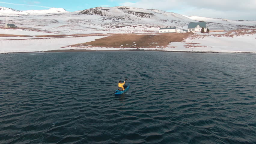 Drone following kayaker from behind on windy winter day.