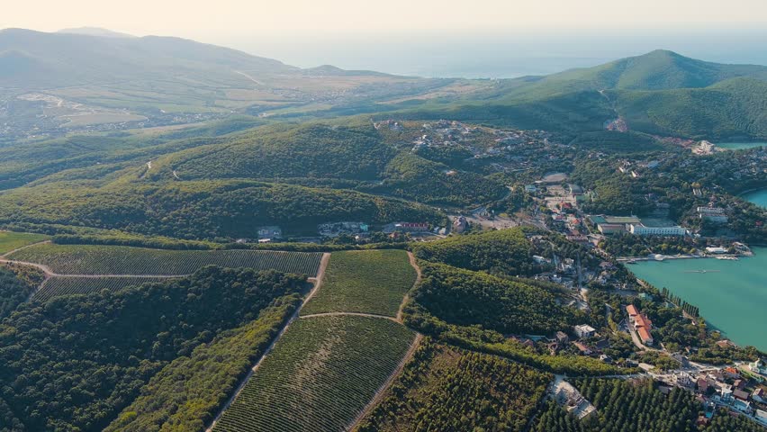 Abrau-Diurso, Krasnodar Krai, Russia. Lake Abrau. Embankment and village. Summer. Fields with vineyards on the hills, Aerial View