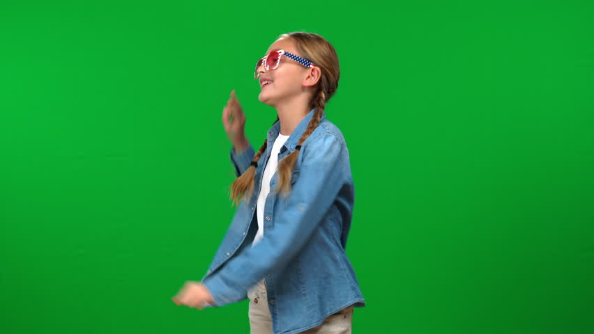 Happy teen Caucasian girl in sunglasses dancing at chroma key background smiling. Portrait of excited cheerful teenager having fun enjoying leisure on green screen Royalty-Free Stock Footage #1103799585