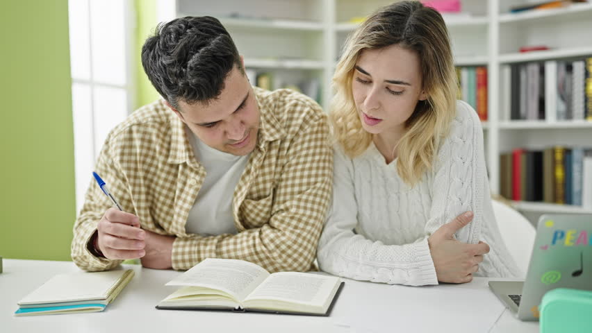 Man and woman students studying together at library university