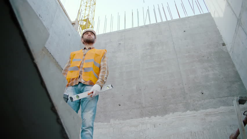 Male worker with toolbox and bubble level tool at the construction site looks to the sides Royalty-Free Stock Footage #1103803047