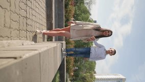 Vertical Video, Happy Family with One Parent Walks on Sunny Day. Attractive Mother Walks with her Child Through City Park. Happiness Motherhood Concept. Family Vacation, Healthy and Active Lifestyle.