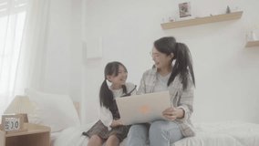 
Asian little young girl learning online class at home with mother. 
