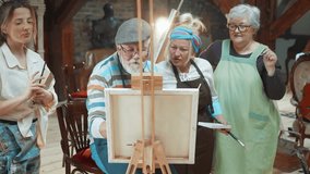 Senior friends attending together at a painting class discussing painting at art school while grandfather painting on a canvas  - Powered by Shutterstock - Get 15% off with code: PIKWIZARD15