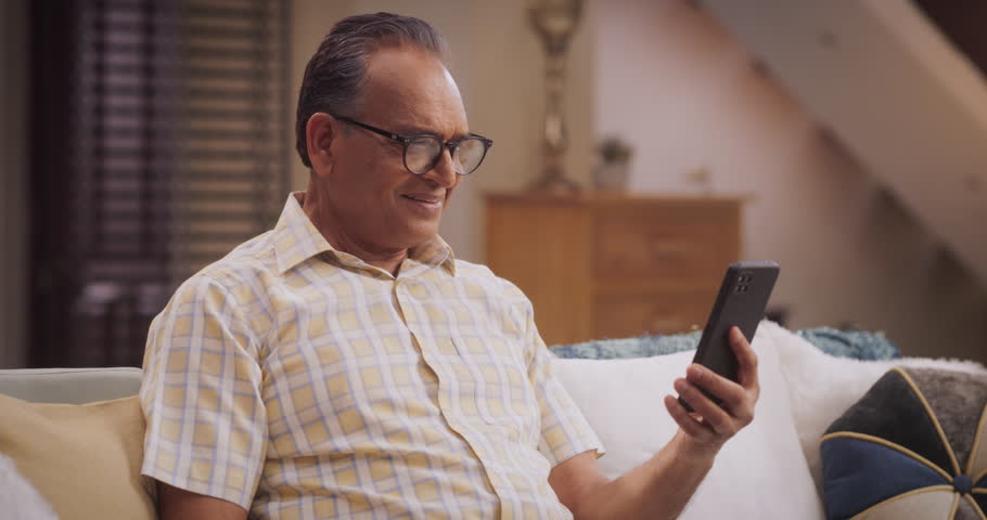 Elderly Indian Man Using Phone for Video Call, Smiling and Happy: Talking with Old Friends and Sharing Life Updates. Cherishing Meaningful Conversations and Laughter with Family Remotely | Shutterstock HD Video #1103811911