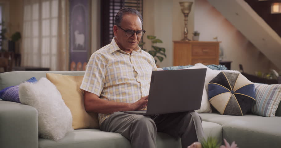 Elderly Indian Man Using Laptop at Home: Using Online Forums to Explore Interests, Delving into History, Arts, and Literature. Cultivating Wisdom and Sharing Stories on Social Media. Medium Static Royalty-Free Stock Footage #1103811925