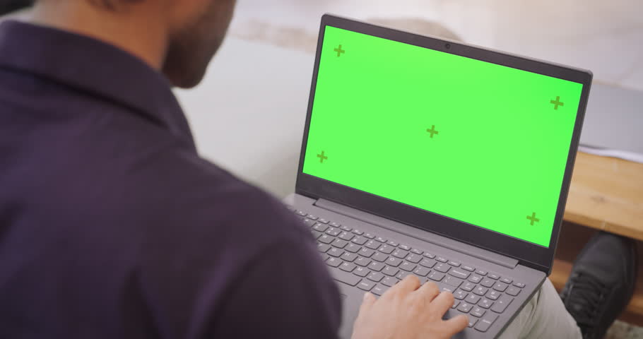 Over-the-Shoulder: Man Using Laptop with Green Chroma Key Screen: Remote Work Collaboration, Video Conferencing. Browsing through Internet, Doing Online Shopping, Using Creative Software.Chroma Key Royalty-Free Stock Footage #1103812123