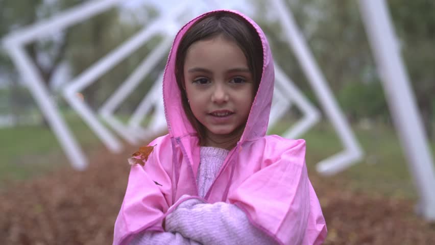 Little girl portrait, then stiks out the tongue. Dressed with a pink raincoat.