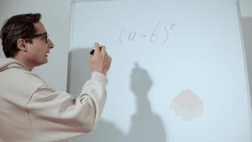 An adult man in glasses and casual clothes writes mathematical formulas on the blackboard. Education and science - Powered by Shutterstock - Get 15% off with code: PIKWIZARD15