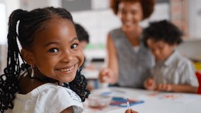 Female elementary school pupil sitting in classroom in art lesson turning and smiling at camera -shot in slow motion - Powered by Shutterstock - Get 15% off with code: PIKWIZARD15
