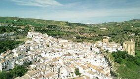 Fixed drone clip of traditional white village buildings in Setenil de las Bodegas, Spain, surrounded by green farmland