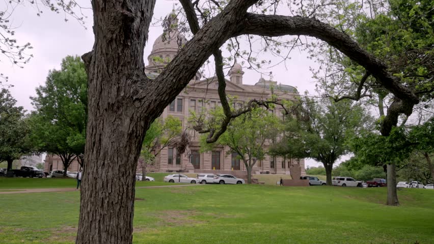 Texas state capitol building in Austin, Texas with gimbal video waking sideways with trees in foreground.