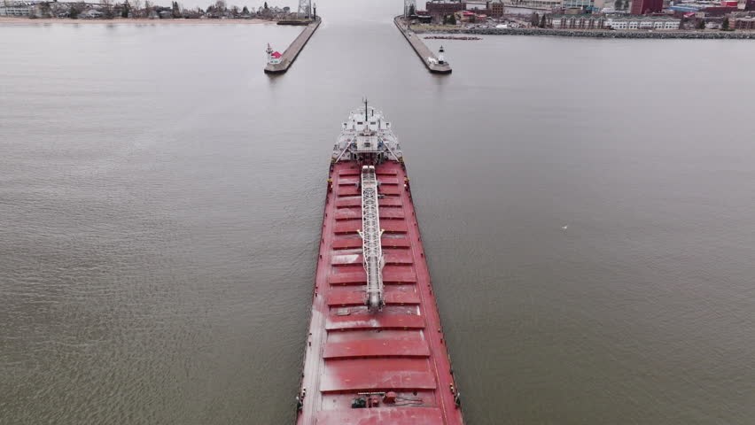Large freight shipping vessel approaching Duluth Aerial Lift Bridge in busy port city harbor of Minnesota