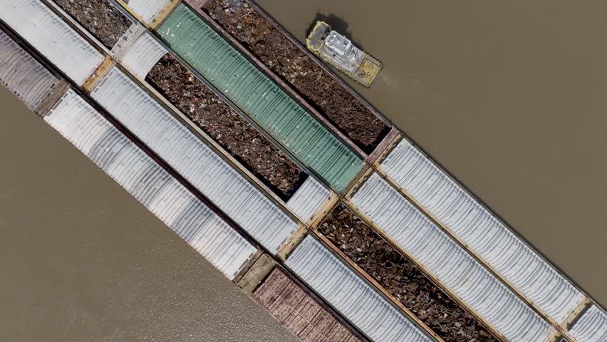 Barges in the Mississippi River with drone video moving up and revealing the Louisiana state capitol building in Baton Rouge, Louisiana.