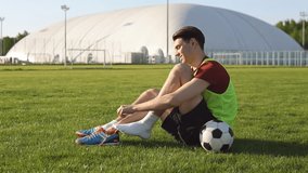 Young male soccer player tying shoelace on football field, slow motion - Powered by Shutterstock - Get 15% off with code: PIKWIZARD15