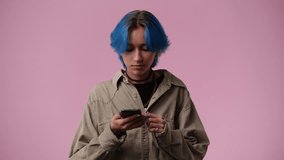 4k video of cute girl with blue hair using phone over pink background.
