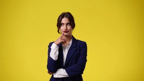 4k video of girl with thoughtful facial expression with pen on yellow background.
