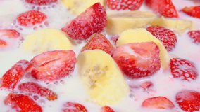 Banana and strawberry slices in milk. Close-up. Slow motion . 4K video.