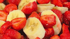Milk is poured on strawberries and bananas cut into slices. Healthy food. Beautiful view. Close-up. Slow motion . 4K video.