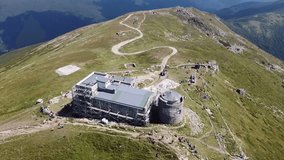 Flying drone around building on top of mountain with mountainscape. Reconstruction of old observatory in Carpathians. Crowd of tourists at the top of Pip Ivan Chornohora, Ukraine. Drone video.