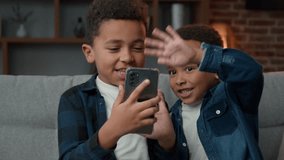 Two little siblings boys African American kids sons friends children brothers has video call online chat virtual meeting with smartphone technology app at home greeting hello to cell phone web camera - Powered by Shutterstock - Get 15% off with code: PIKWIZARD15