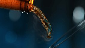 Pouring Beer to Glass from Bottle. Stream of Golden Carbonated Liquid Flows in Slow Motion on Dark Blue Background, Filling Glassware - Powered by Shutterstock - Get 15% off with code: PIKWIZARD15