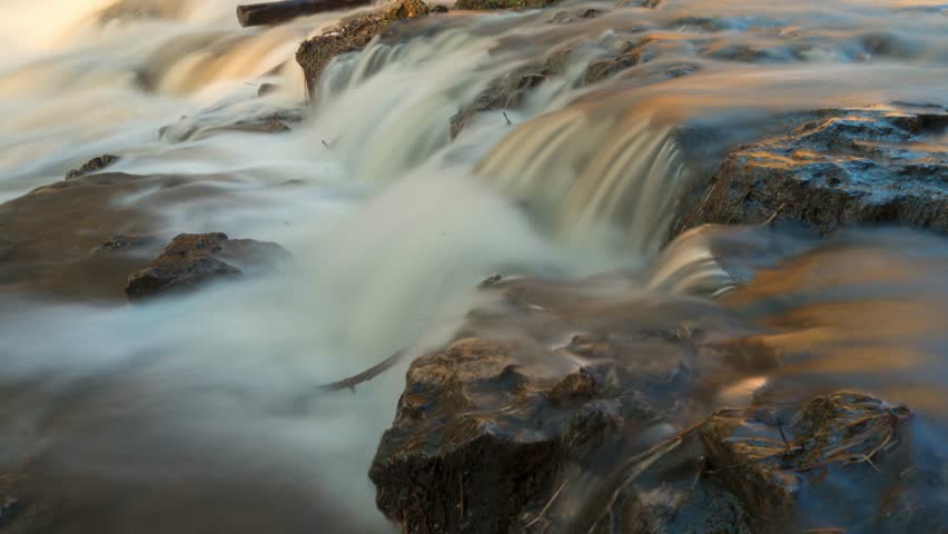 Cinematic timelapse of smooth waterfall stream flowing through rocks