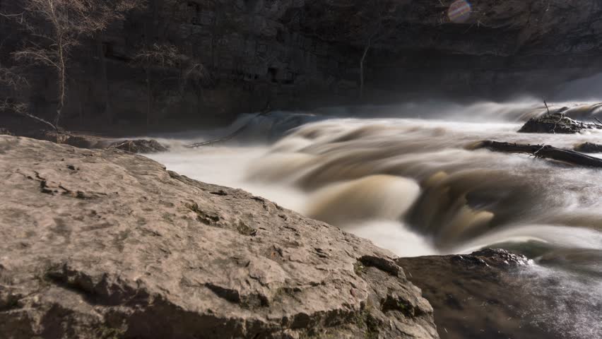 Smooth rocky river stream flowing during the day, timelapse of willow river waterfall